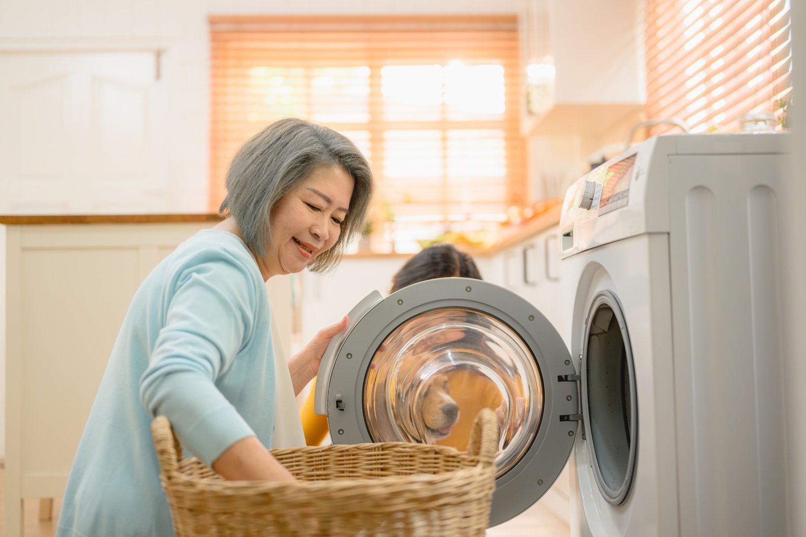 a beautiful senior woman, takes care of the laundry using a washing machine